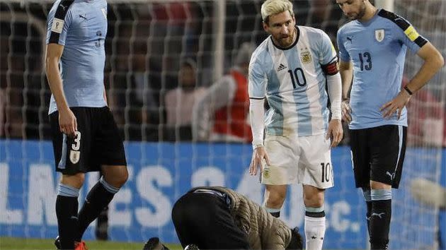 The supporter kneeling down to kiss Messi's boots.