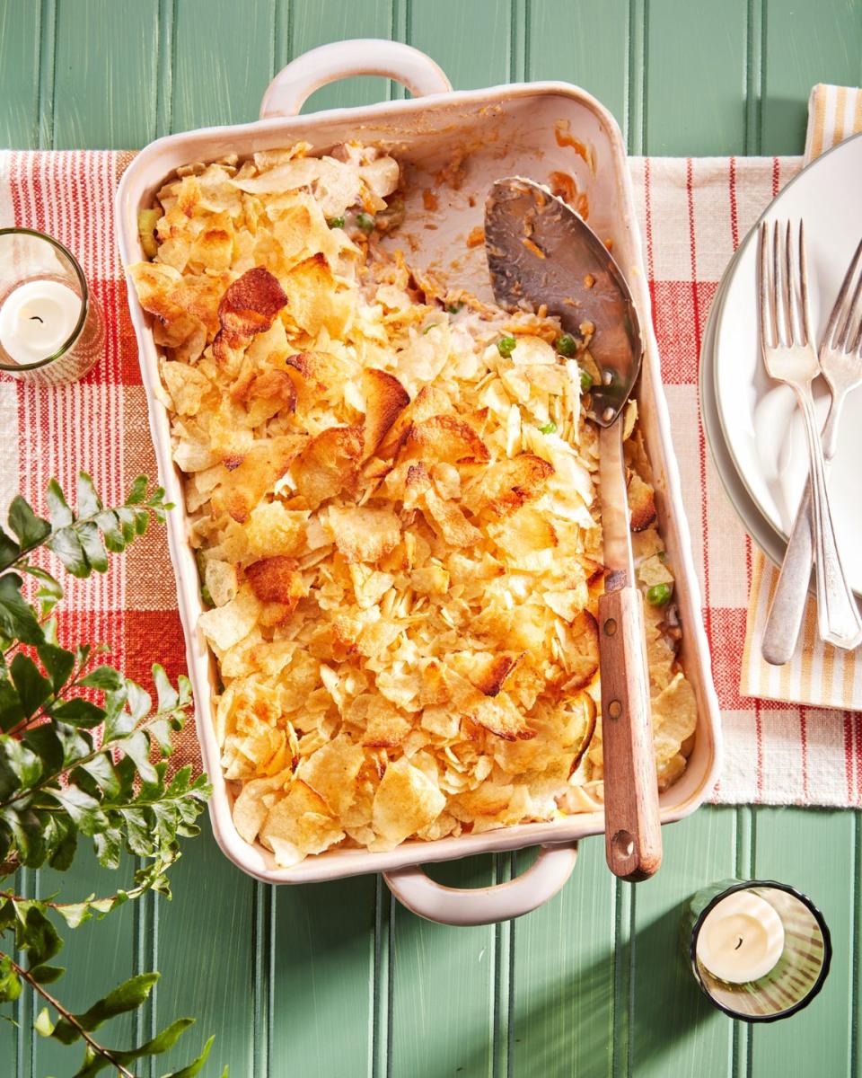 tuna noodle casserole in a light cream colored rectangle baking dish with a spoon for serving