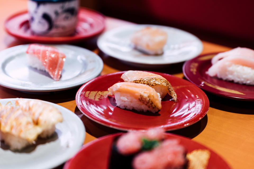 Sushi and Sashimi. Dishes of Sushi and Sashimi rolling on conveyer belt.