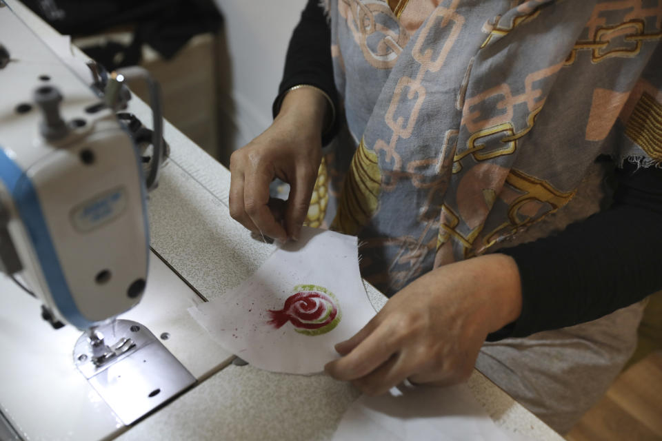 Elham Karami sews a protective face mask at a workshop of Bavar charity in Tehran, Iran, Monday, Nov. 23, 2020. As the coronavirus pandemic ravages Iran, a women’s group hopes to empower its members by helping them make and sell face masks. (AP Photo/Vahid Salemi)