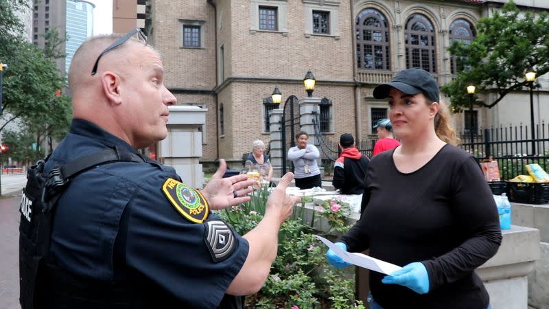Houston Police Sergeant Jeff Richard issues a warning to Food Not Bombs volunteer Shere Dore for sharing food with the homeless in Houston, TX