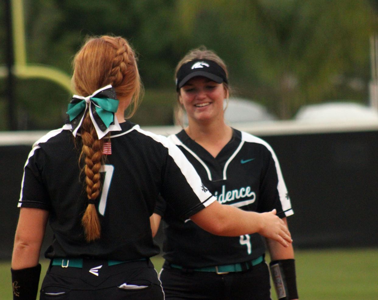 Providence's Ella Roberson (7) and Kayla Burmeister (4) smile during a break in the action while heading to their positions between innings in an April game.