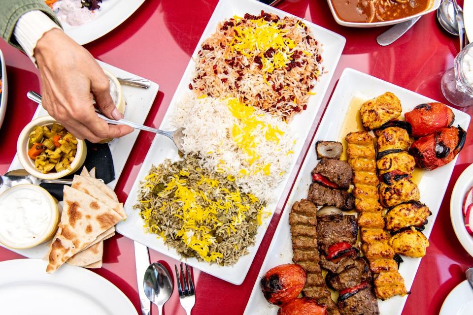 A hand dips a spoon into rice that sits among a large selection of dishes at Javan.