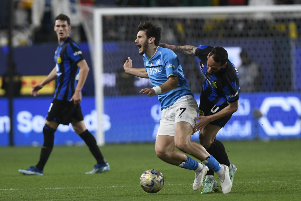 Napoli's Khvicha Kvaratskhelia, left, is pushed by Inter Milan's Hakan Calhanoglu, right, during the Italian Super Cup final soccer match between Inter Milan and Napoli at Al Awwal Park Stadium in Riyadh, Saudi Arabia, Monday, Jan. 22, 2024. (AP Photo)