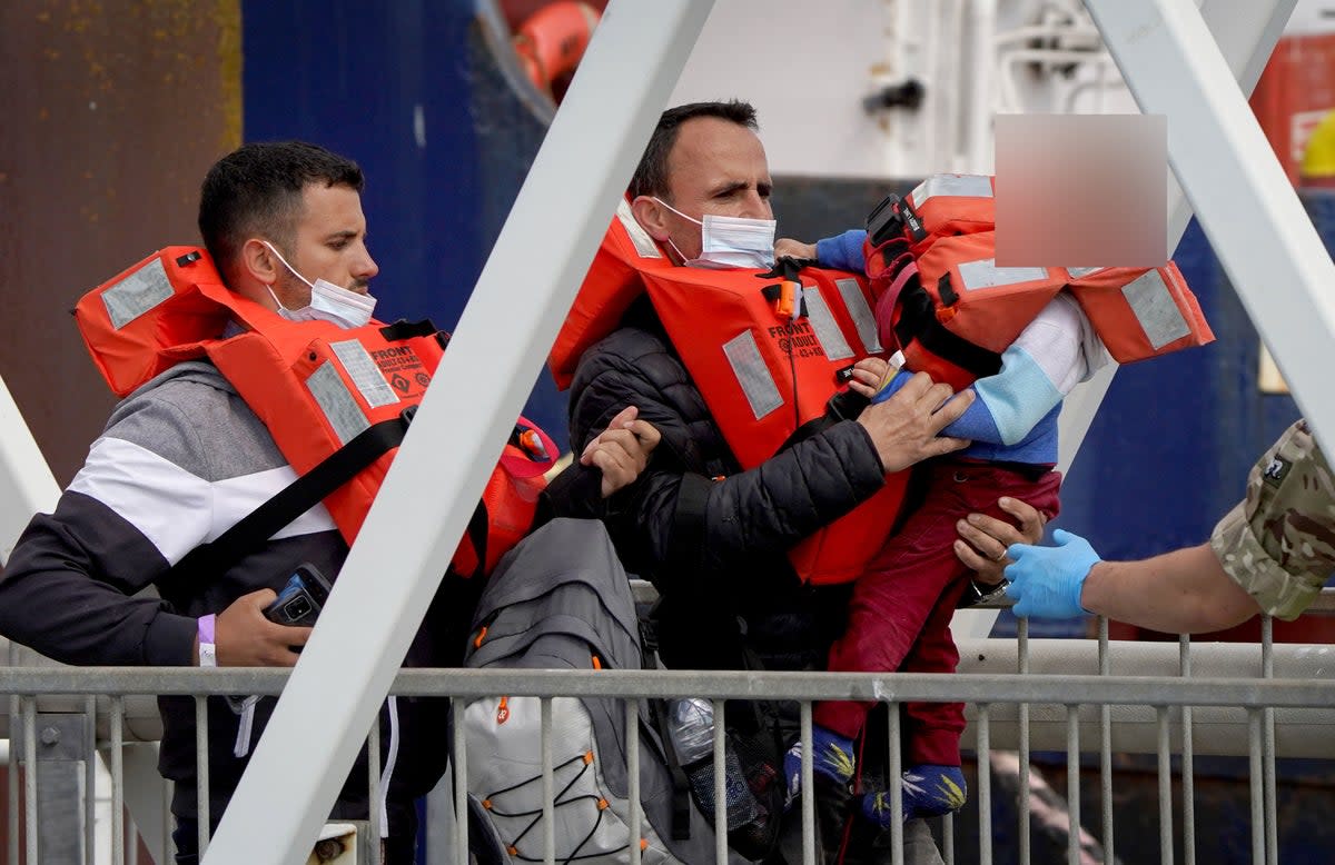 A man carries a distressed young child amongst a group of people thought to be migrants as they are brought in to Dover, Kent (PA)