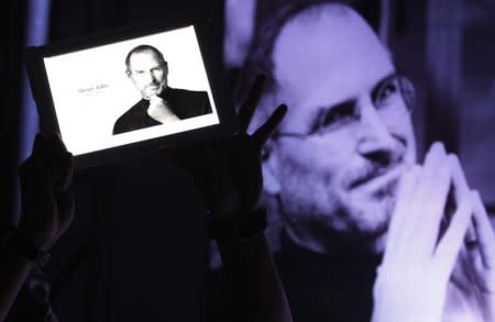 FILE PHOTO - A man holds an iPad displaying a photo of Steve Jobs during a 'Steve Jobs Day' memorial day event in Manila October 14, 2011.  REUTERS/Romeo Ranoco