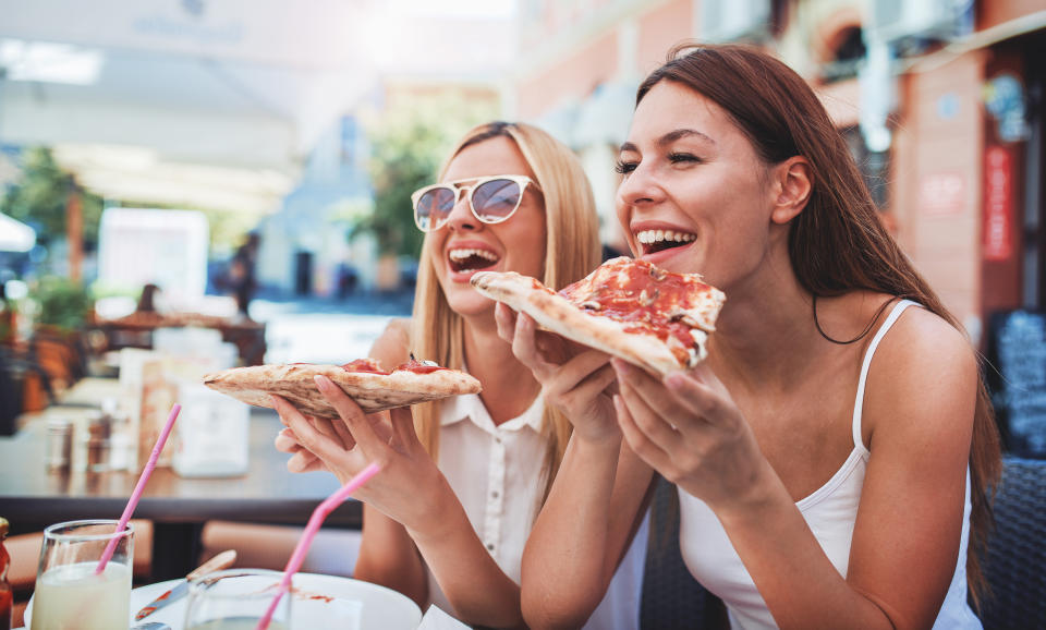 Pizza time. Handsome smiling women eating pizza, having fun together in the restaurant. Consumerism, food, lifestyle concept
