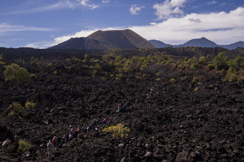 Geólogos, vulcanólogos y sismólogos caminan sobre una antigua capa de lava hacia el cráter del volcán Paricutín, en Angahuan, México, el miércoles 22 de febrero de 2023. El nacimiento del Paricutín el 20 de febrero de 1943 y sus nueve años de erupción fueron la piedra angular en el estudio de los llamados volcanes monogenéticos, contó Stavros Meletlidis, un investigador griego del Instituto Nacional Geográfico de España. (AP Foto/Eduardo Verdugo)