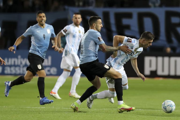 Giovani Lo Celso pierde la pelota presionado por el uruguayo Matias Vecino; la línea de volantes argentinos casi no tuvo juego durante el primer tiempo. (Raúl Martínez/Pool Via AP)