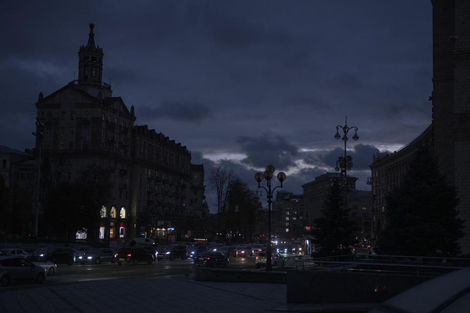 Cars pass at twilight in Kyiv downtown, Ukraine, Monday, Oct. 31, 2022. Rolling blackouts are increasing across Ukraine as the government rushes to stabilise the energy grid and repair the system ahead of winter. (AP Photo/Andrew Kravchenko)