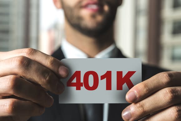 Man holding white card that says "401K" in red letters.