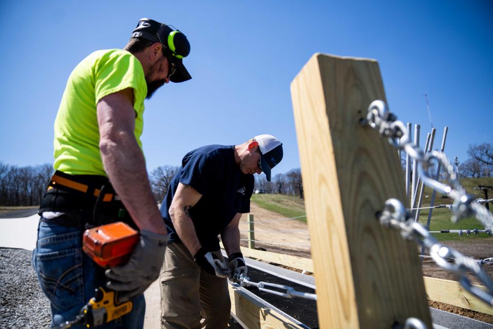 Brad Wallace and Shawn Warren of the Polk County Conservation maintenance team work on installing a ski lift system for the park's new synthetic ski Tuesday, April 8, 2024, at the Sleepy Hollow Sports Park in Des Moines.