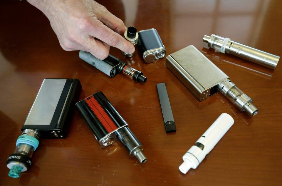 In this April 10, 2018 file photo, a high school principal displays vaping devices that were confiscated from students in such places as restrooms or hallways at the school in Massachusetts.