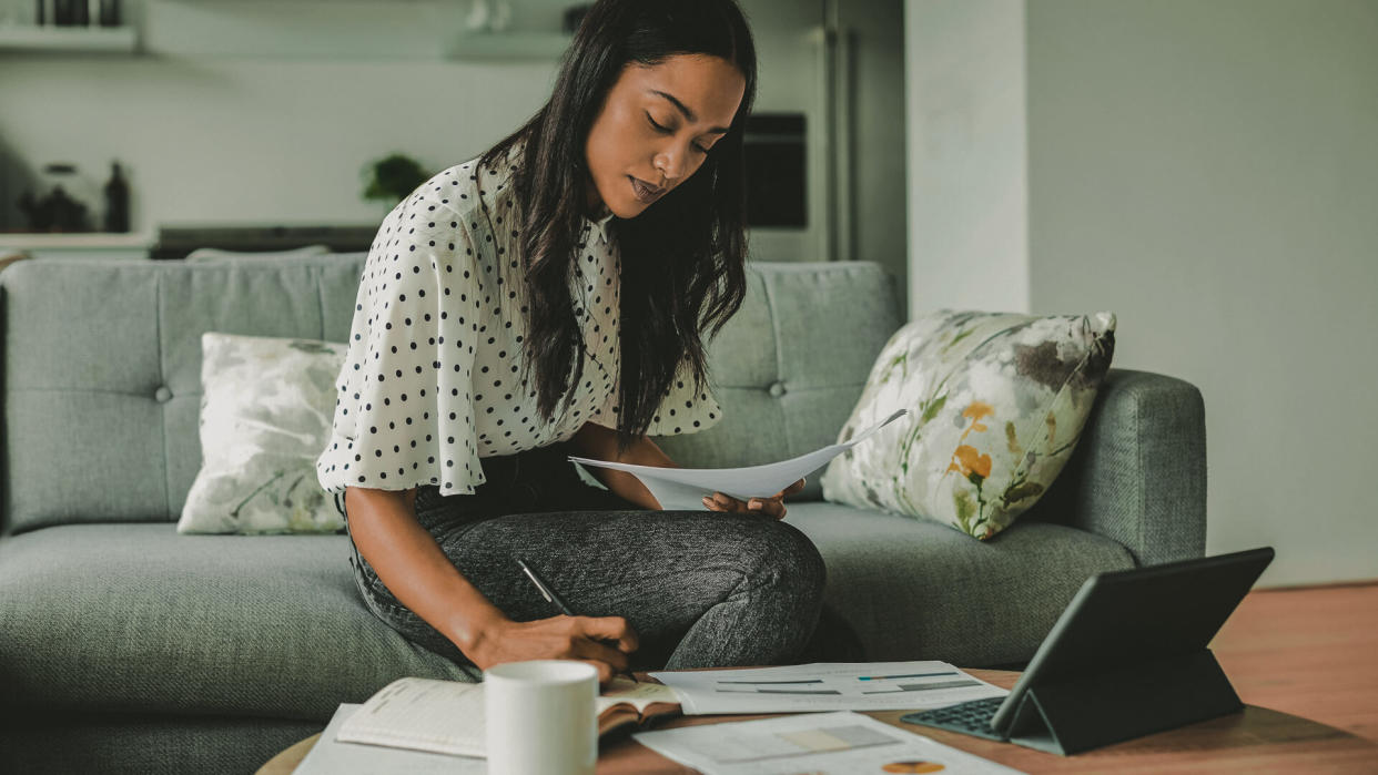 Young woman analyzing bills while writing in diary.