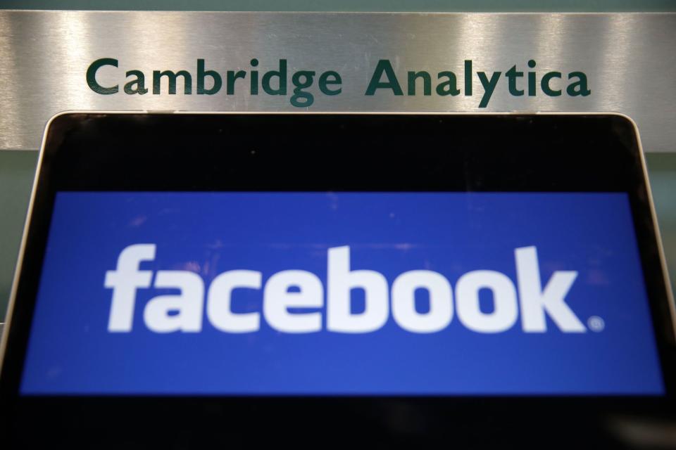 Catastrophe: A laptop showing the Facebook logo is held alongside a Cambridge Analytica sign at the entrance to the building housing the offices of Cambridge Analytica, in central London on March 21, 2018. Photo: DANIEL LEAL-OLIVAS/AFP/Getty Images