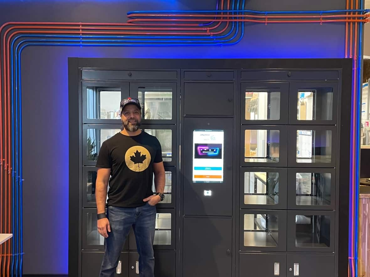 Amir Rahim, owner of Grounded Kitchen, stands in front of the automated food lockers at his business where customers can pick up their meals after ordering online.  (Submitted by Amir Rahim - image credit)