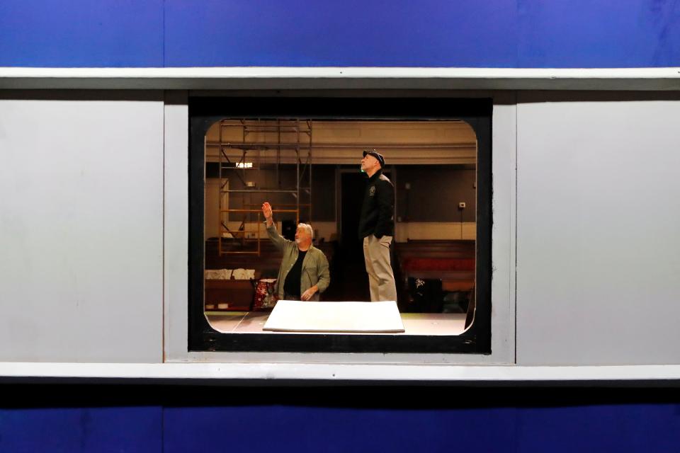 Paul Sardinha, who will play Monsieur Bouc, and Eric Paradis, Your Theater community liaison, are seen through a train window set as they discuss lighting for upcoming the Murder on the Orient Express, the first show by Your Theater at the new Steeple Playhouse inside the former First Baptist Church on William Street in New Bedford.