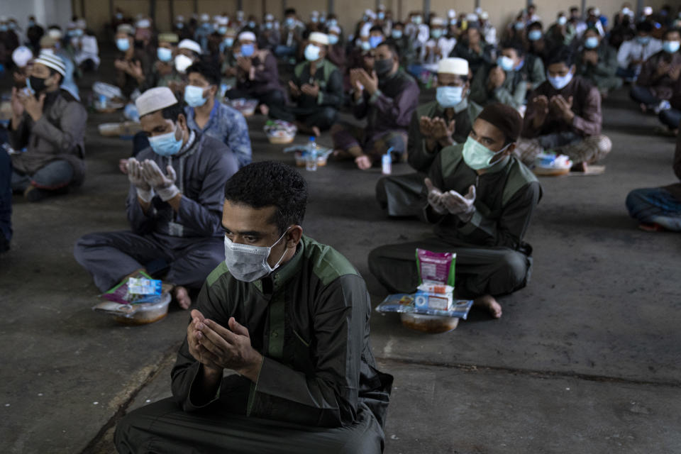 SINGAPORE - MAY 24: Migrant workers dressed in new clothes and protective face masks pray during a Eid al-Fitr celebration with non-governmental organisations Migrant Workers Centre (MWC), Majlis Ugama Islam Singapura (MUIS), Inter-Religious Organisation, Singapore (IRO), and Singapore Bangladesh Society in their factory converted dormitory on May 24, 2020 in Singapore. (Photo by Ore Huiying/Getty Images)