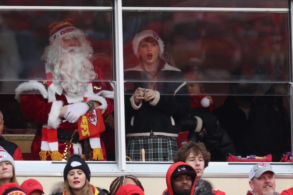 Taylor Swift appears at a December 25 Chiefs game against the Raiders wearing a Santa hat with Travis Kelce's number on it.