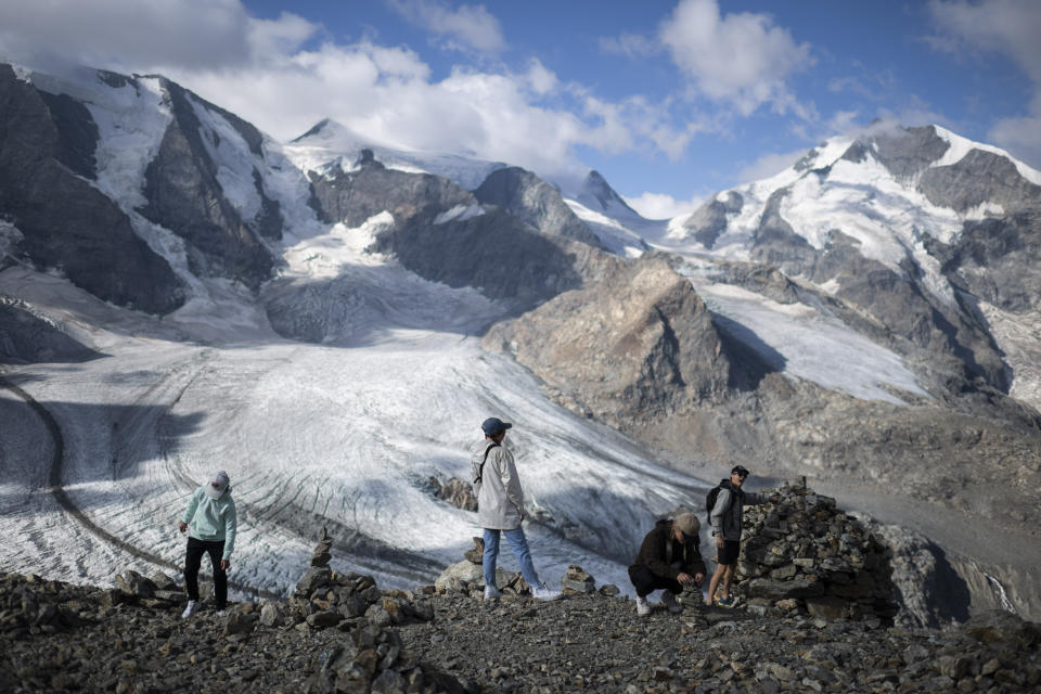 People stay in front of the Bernina mountain group with the Pers and Morteratsch glaciers in Pontresina, Switzerland, Wednesday, August 10, 2022. (Gian Ehrenzeller/Keystone via AP)