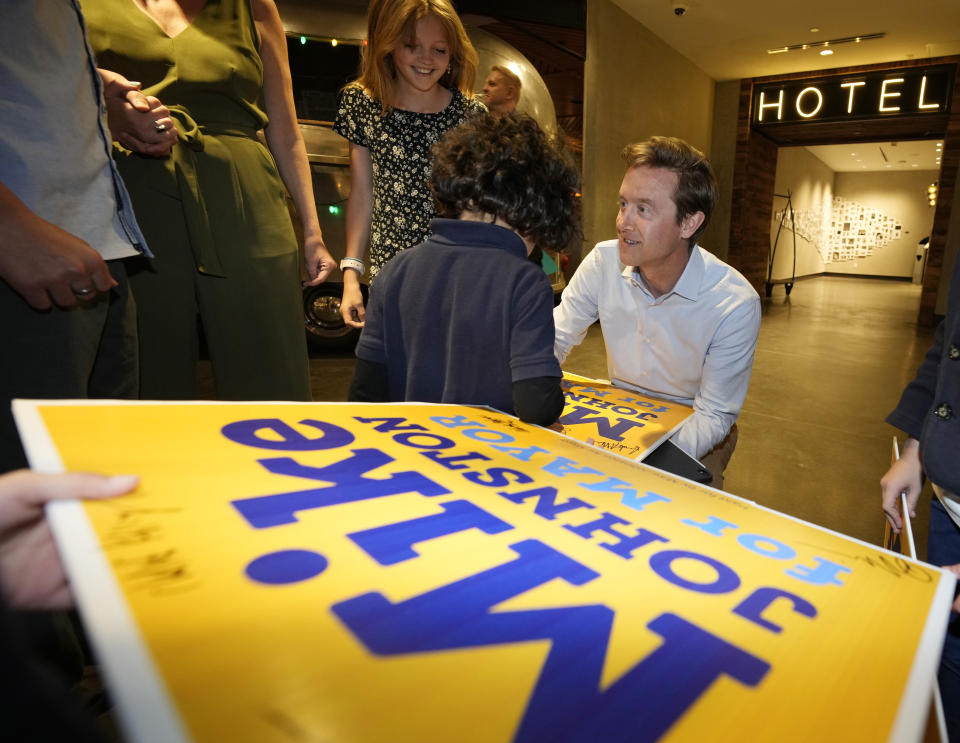 Denver mayoral candidate Mike Johnston autographs yard signs for the children of his supporters before entering an election eve watch party in a hotel late Tuesday, April 4, 2023, in lower downtown Denver. Johnston and Kelly Brough were the top vote-getters in the race, which featured 16 candidates. (AP Photo/David Zalubowski)