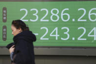 A woman walks by an electronic stock board of a securities firm in Tokyo, Tuesday, Dec. 3, 2019. Asian shares slipped Tuesday, following a drop on Wall Street amid pessimism over U.S.-China trade tensions. (AP Photo/Koji Sasahara)