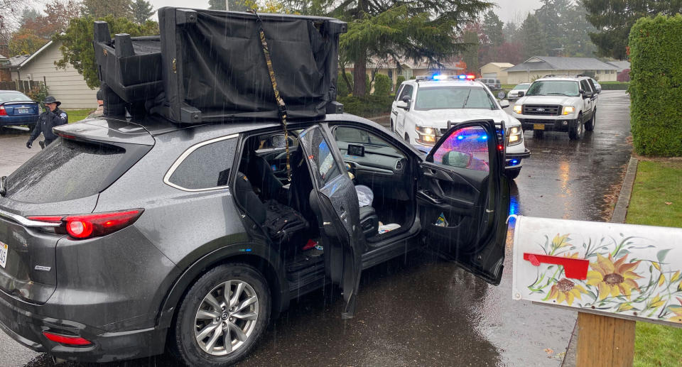 A car with a sofa strapped to the top of it.