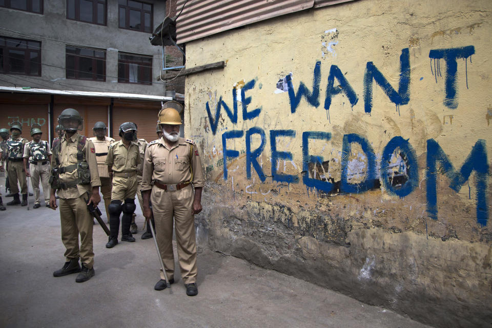 FILE - In this Aug. 12, 2016, file photo, Indian policemen stand guard during a curfew in Srinagar, Indian-controlled Kashmir. Modi’s vision of a Hindu India took a leap forward with his government’s decision in August, 2019, to subsume Kashmir into the federal government by eliminating its special status and allowing anyone to buy property and move into the state, raising fears among residents that they will lose their distinct identity. Modi’s home minister, Amit Shah, considered the architect of the Hindu nationalist-led government’s aggressive agenda to convert India from a secular, multicultural democracy into a distinctly Hindu, culturally and politically homogenous state, sold the new policy on Kashmir to parliament by equating it with Pakistan, India’s staunch foe. (AP Photo/Dar Yasin, File)