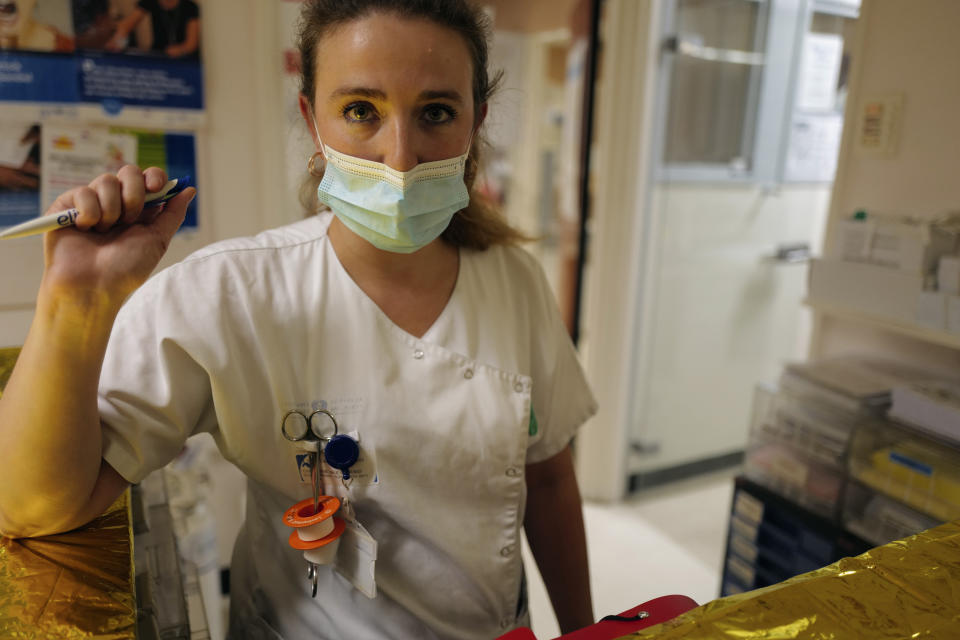 Medical staff member Alexandra Pichon Dignac pauses as Lolita Andela and Caroline Erganian, arrive on the eve of their surgery, at Bichat Hospital, AP-HP, in Paris, Tuesday, Dec. 1, 2020. Hospitals are increasingly grappling with giant backlogs of surgeries that were postponed when COVID-19 hit. One of the biggest hospitals in Paris, Bichat Hospital, this month reopened all 22 of its operating rooms. It is once again performing surgeries that were stopped during virus surges that pushed France's death toll past 55,000. (AP Photo/Francois Mori)