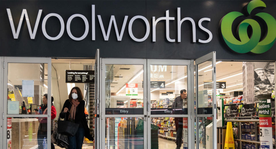 Photo shows woman wearing mask walking out of Woolworths store.