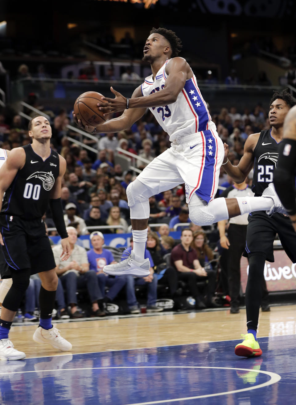 Philadelphia 76ers' Jimmy Butler, center, shoots as he gets between Orlando Magic's Aaron Gordon (00) and Wesley Iwundu (25) during the first half of an NBA basketball game Wednesday, Nov. 14, 2018, in Orlando, Fla. (AP Photo/John Raoux)