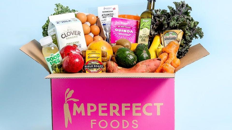 imperfect foods pink box with a variety of groceries on a blue background