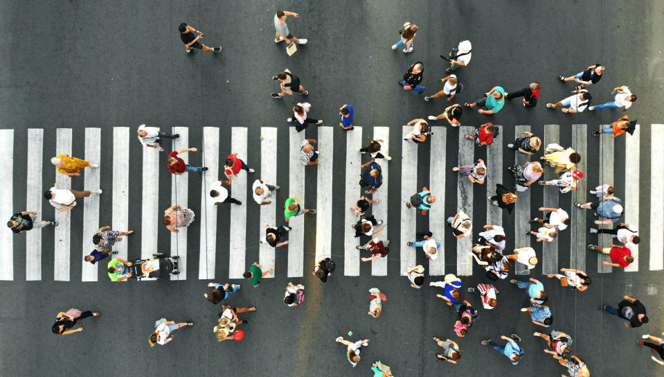 Aerial. People crowd. Many people going through the pedestrian crosswalk. Top view.