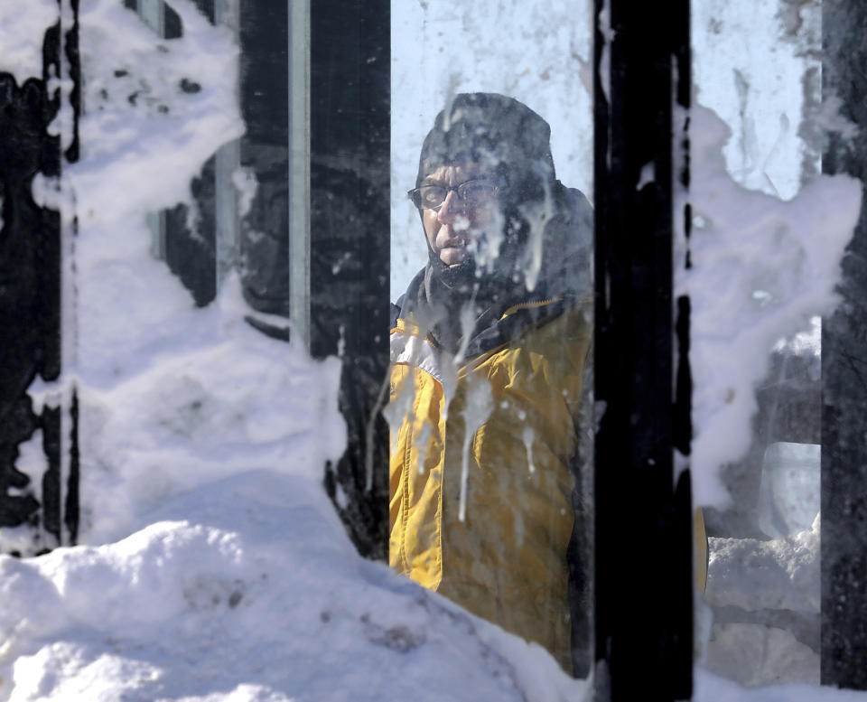 Paul Kollauf is framed by an accumulation of snow on the panes of a bus shelter while waiting for a bus on East Washington Avenue in Madison, Wis., on Jan. 30, 2019. (Photo: John Hart/Wisconsin State Journal via AP)