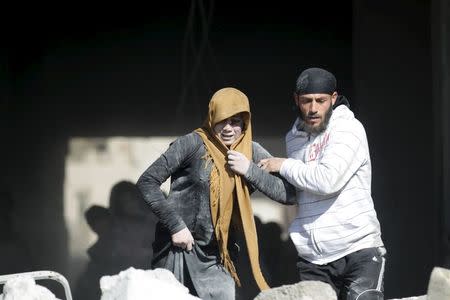 A man helps an injured woman in a site hit by what activists said were airstrikes carried out by the Russian air force in the rebel-controlled area of Maaret al-Numan town in Idlib province, Syria January 9, 2016. REUTERS/Khalil Ashawi