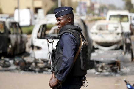 A soldier stands guard in front of burned cars across the street from Splendid Hotel in Ouagadougou, Burkina Faso, January 17, 2016, a day after security forces retook the hotel from al Qaeda fighters who seized it in an assault that killed two dozen people from at least 18 countries and marked a major escalation of Islamist militancy in West Africa. REUTERS/Joe Penney