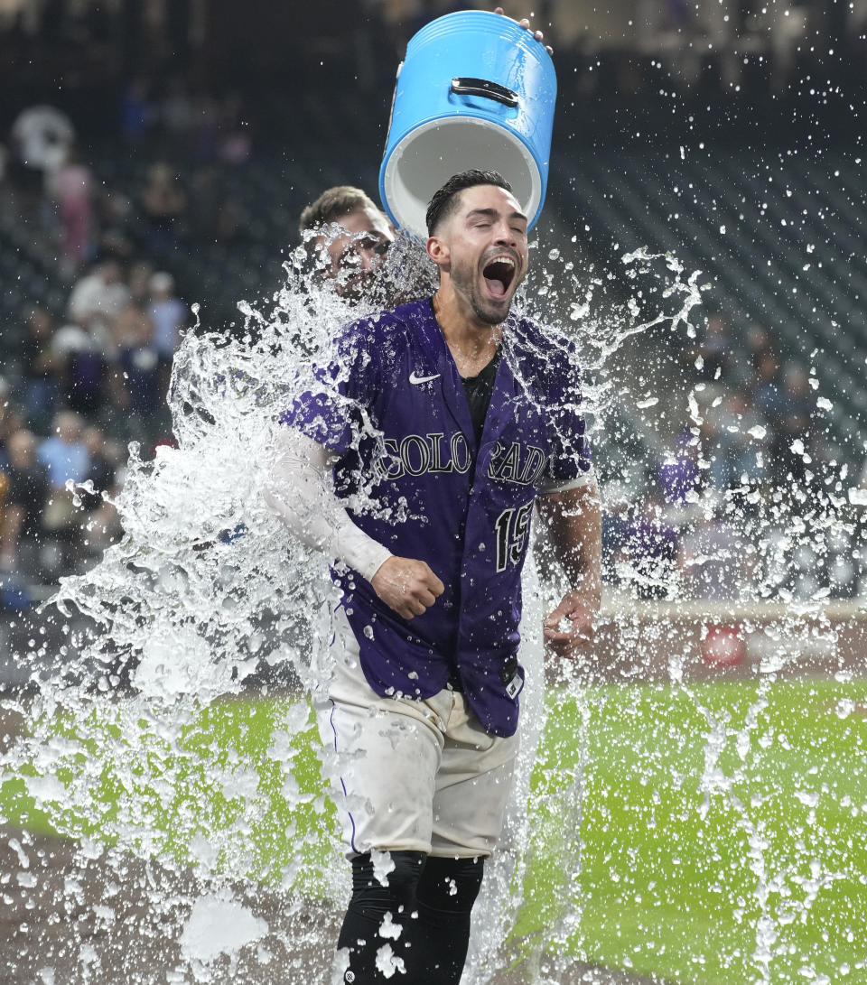 Colorado Rockies' Randal Grichuk is doused by Charlie Blackmon while being interviewed after the team's baseball game against the Milwaukee Brewers on Tuesday, Sept. 6, 2022, in Denver. Grichuk hit a three-run home run for the victory. (AP Photo/David Zalubowski)