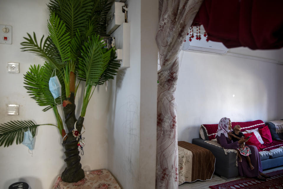 Fatima Muhtar, Sudanese migrant holds sit with her daughter at their living room in their house in south Tel Aviv, Israel, Friday, Oct. 30, 2020. After Israel and Sudan agreed this month to normalize ties, some 6,000 Sudanese migrants in Israel are again fearing for their fate. Israel has long grappled with how to deal with its tens of thousands of African migrants. (AP Photo/Oded Balilty)