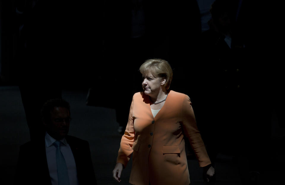 German Chancellor Angela Merkel walks through a beam of sunlight as she arrives for a special session of the Germany Parliament Bundestag in Berlin, Germany, Thursday, July 19, 2012. Germany's Parliament is interrupting its summer break to vote on a rescue package worth up to euro 100 billion (US dollar 122 billion) for Spain's ailing banks. (AP Photo/Gero Breloer)