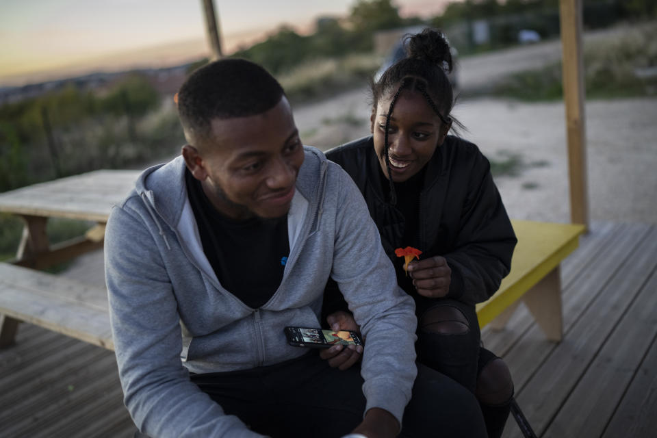 Melissa reacts as Jamel tastes a Garden Nasturtium flower which has a spicy flavour at the Capri farm in Marseille's northern neighbourhoods, southern France, Tuesday, Oct. 26, 2021. Urban gardens are sprouting hope in drug- and violence-plagued neighborhoods of Marseille. From publicly funded city-wide initiatives to residents taking it upon themselves to start cultivating the land around them, urban farming is changing the landscape and creating a space for community. (AP Photo/Daniel Cole)