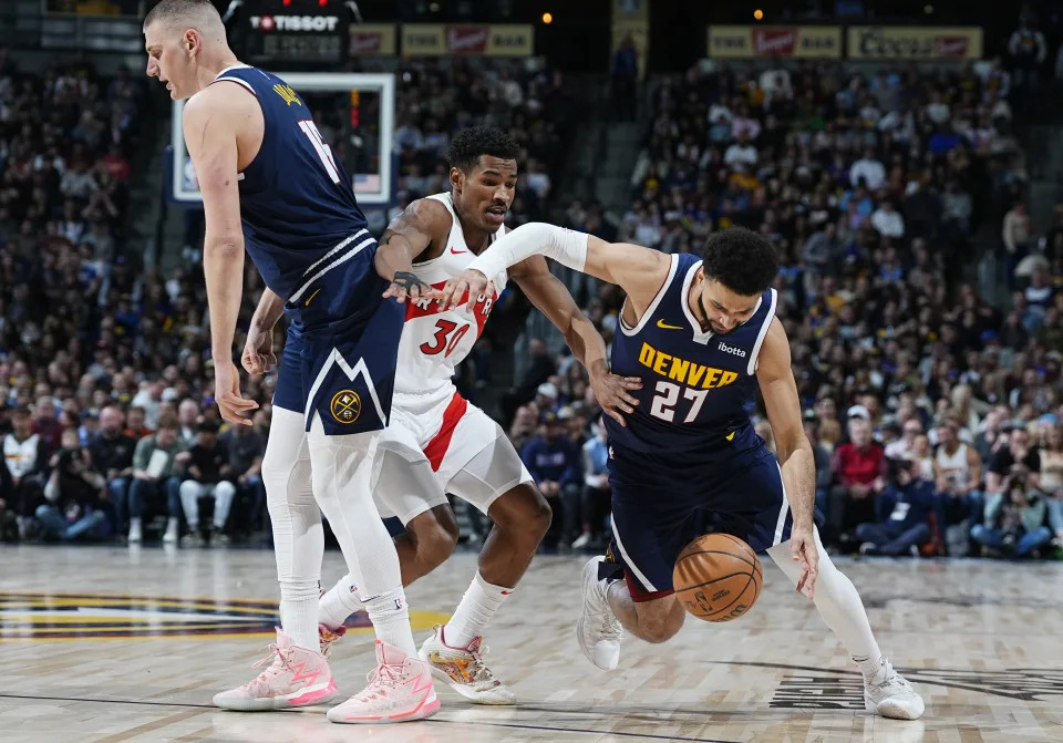 Denver Nuggets guard Jamal Murray, right, drives past Toronto Raptors guard Ochai Agbaji, center, as Nuggets center Nikola Jokic, left, sets a pick in the first half of an NBA basketball game Monday, March 11, 2024, in Denver. (AP Photo/David Zalubowski)