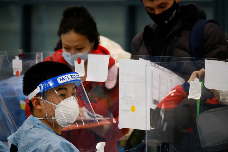 A worker wearing protective gear checks passengers from overseas as they arrive at the Incheon International Airport, in Incheon