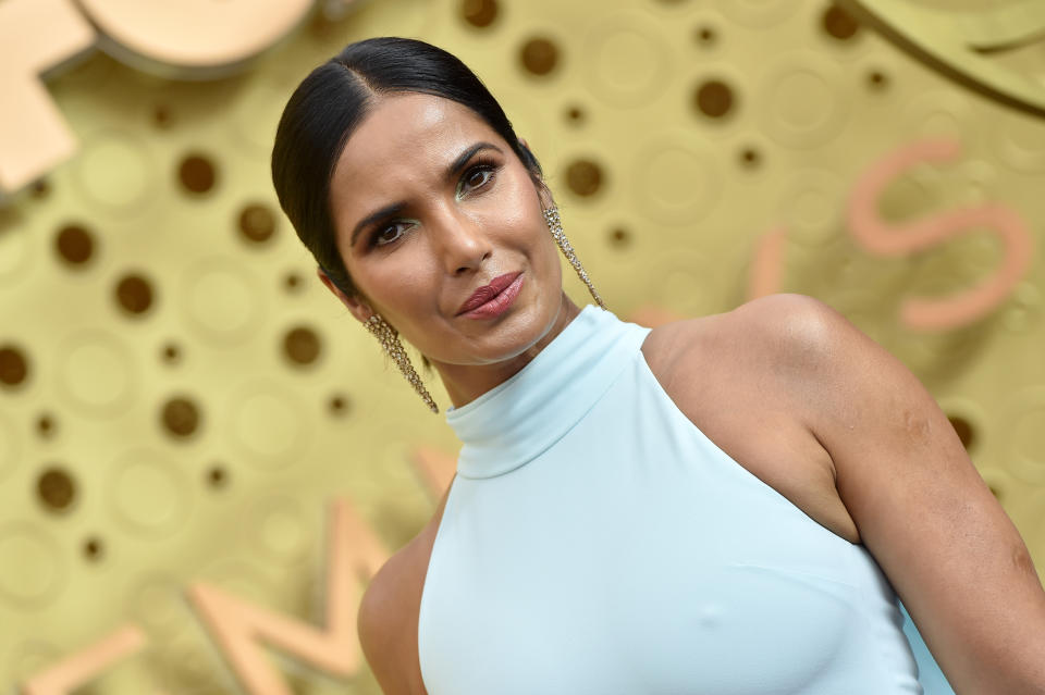 Padma Lakshmi looks at the camera in a white halterneck dress