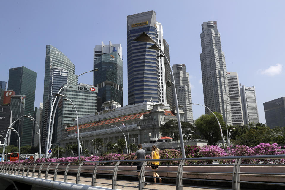 People walk along a footbridge in front of the financial district in Singapore, Thursday, June 7, 2018, in Singapore. U.S. President Donald Trump and North Korean leader Kim Jong Un will meet at a luxury resort in Singapore next week for nuclear talks, the White House said Tuesday. (AP Photo/Wong Maye-E)