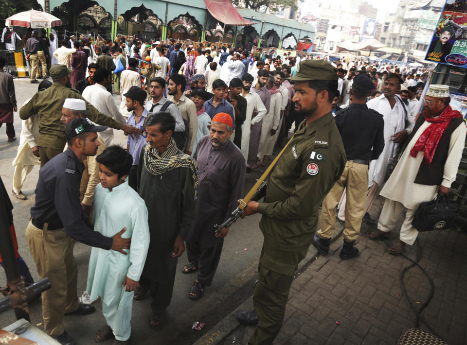 In this Tuesday, Oct. 30, 2018, photo, Pakistani police officers check worshippers visiting the famous shrine of Sufi Data Gunj Baksh in Lahore, Pakistan. (AP Photo/K.M. Chaudary)