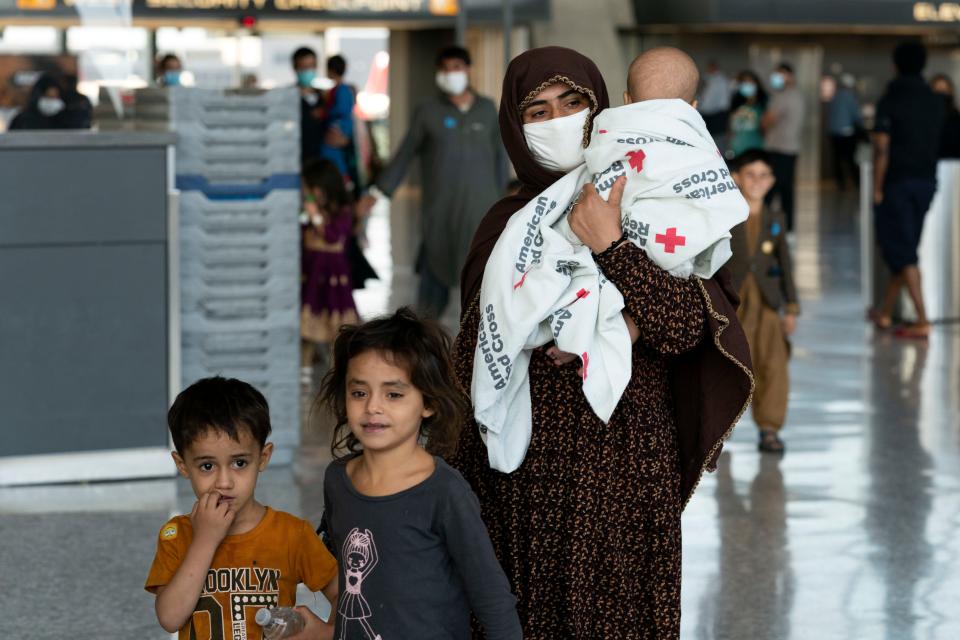 Families evacuated from Kabul, Afghanistan, walk through the terminal before boarding a bus after they arrived at Washington Dulles International Airport, in Chantilly, Virginia, on Aug. 27, 2021.