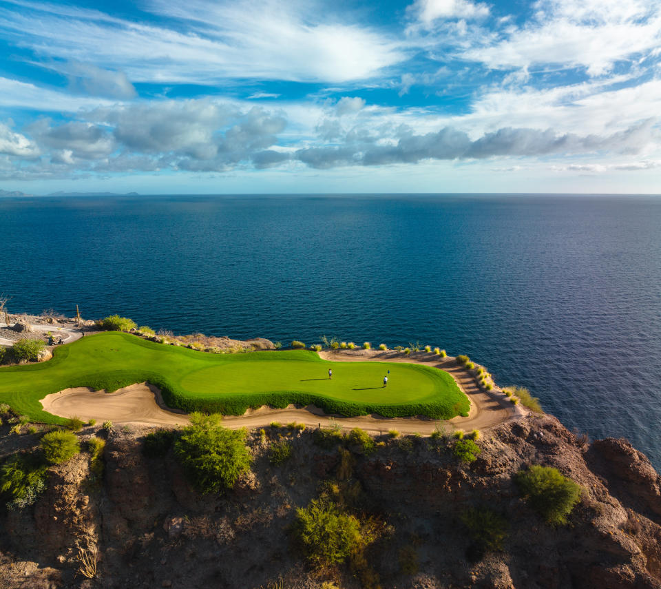 Golfers play on the course at Villa del Palmar at the Islands of Loreto above the dark blue ocean