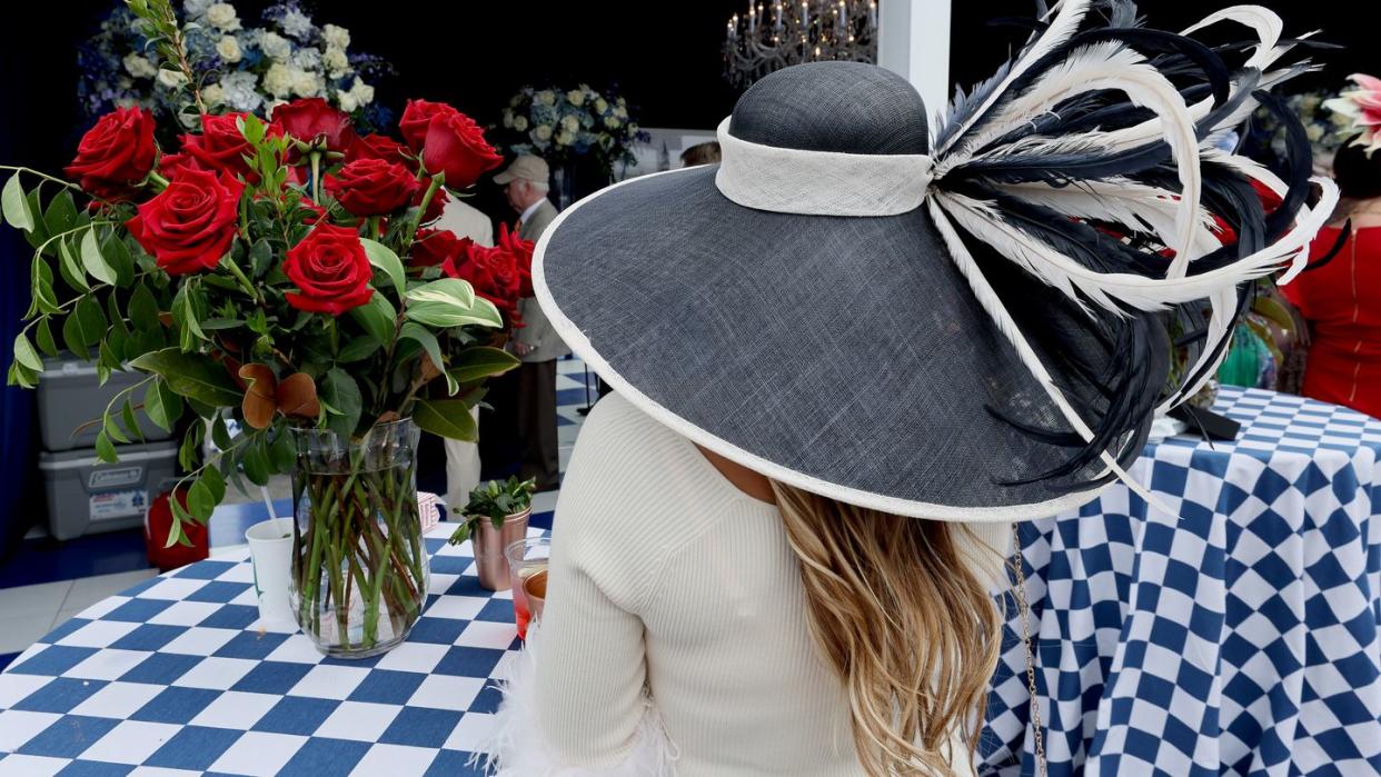 a woman in a black and white hat next to a bouquet of roses