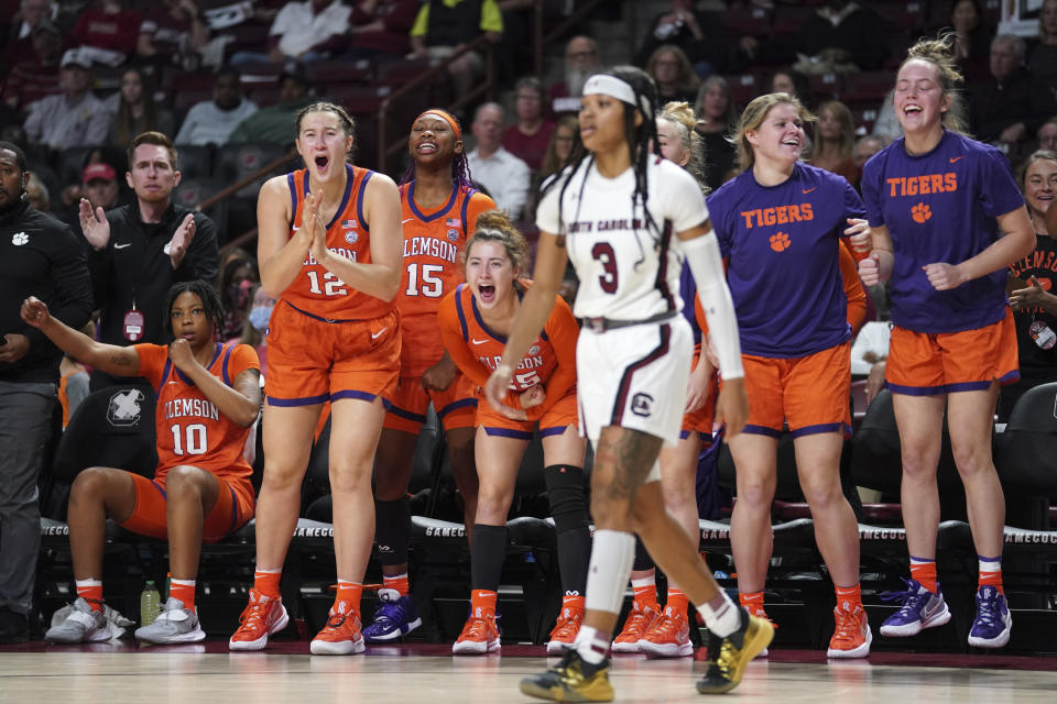 The Clemson bench celebrates a play as South Carolina guard Destanni Henderson (3) walks by during the first half of an NCAA college basketball game Wednesday, Nov. 17, 2021, in Columbia, S.C. (AP Photo/Sean Rayford)