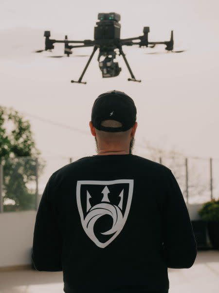 a man wearing a black jacket with a helicopter in the background